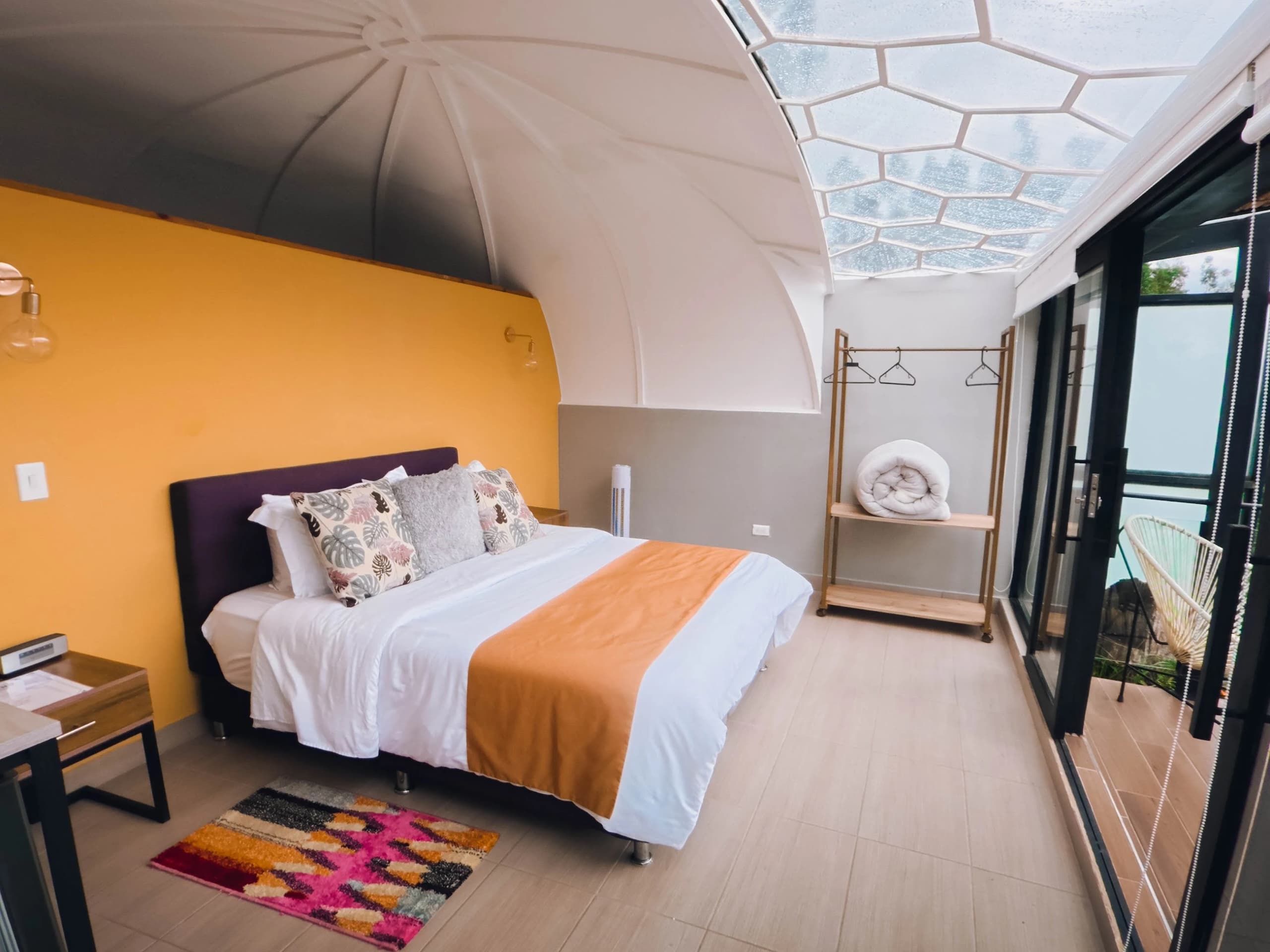 Interior de un domo, con la cama frente al ventanal abierto