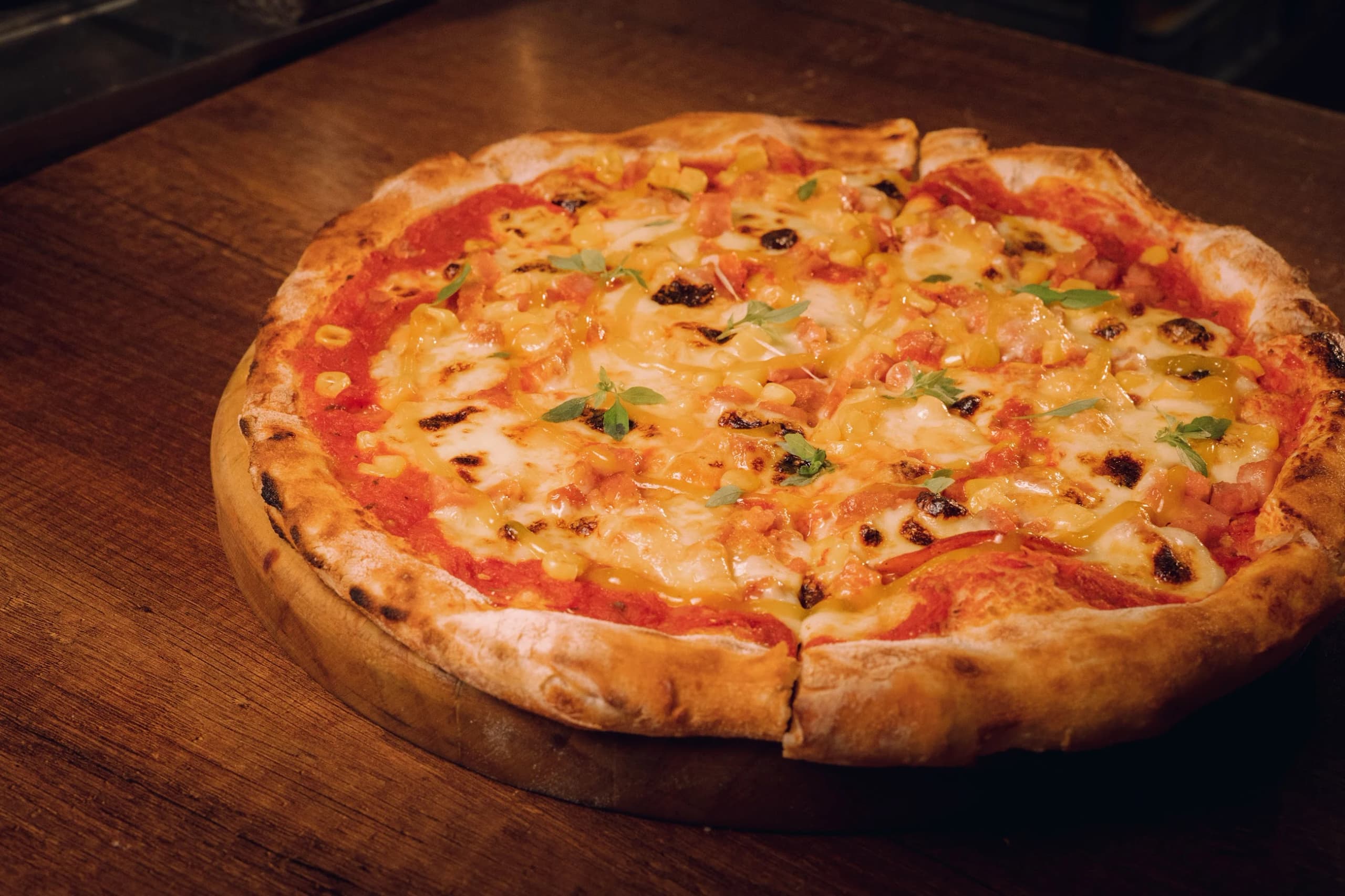 Una pizza recién salida del horno, sobre tabla de madera
